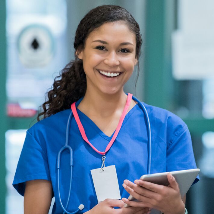 Friendly emergency room nurse smiles while holding electronic medical record