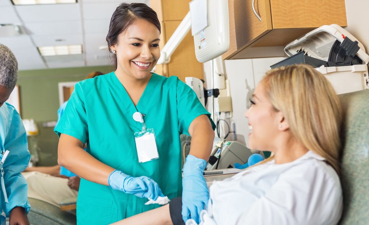 Nurse bandaging arm after patient donates blood in hospital bank